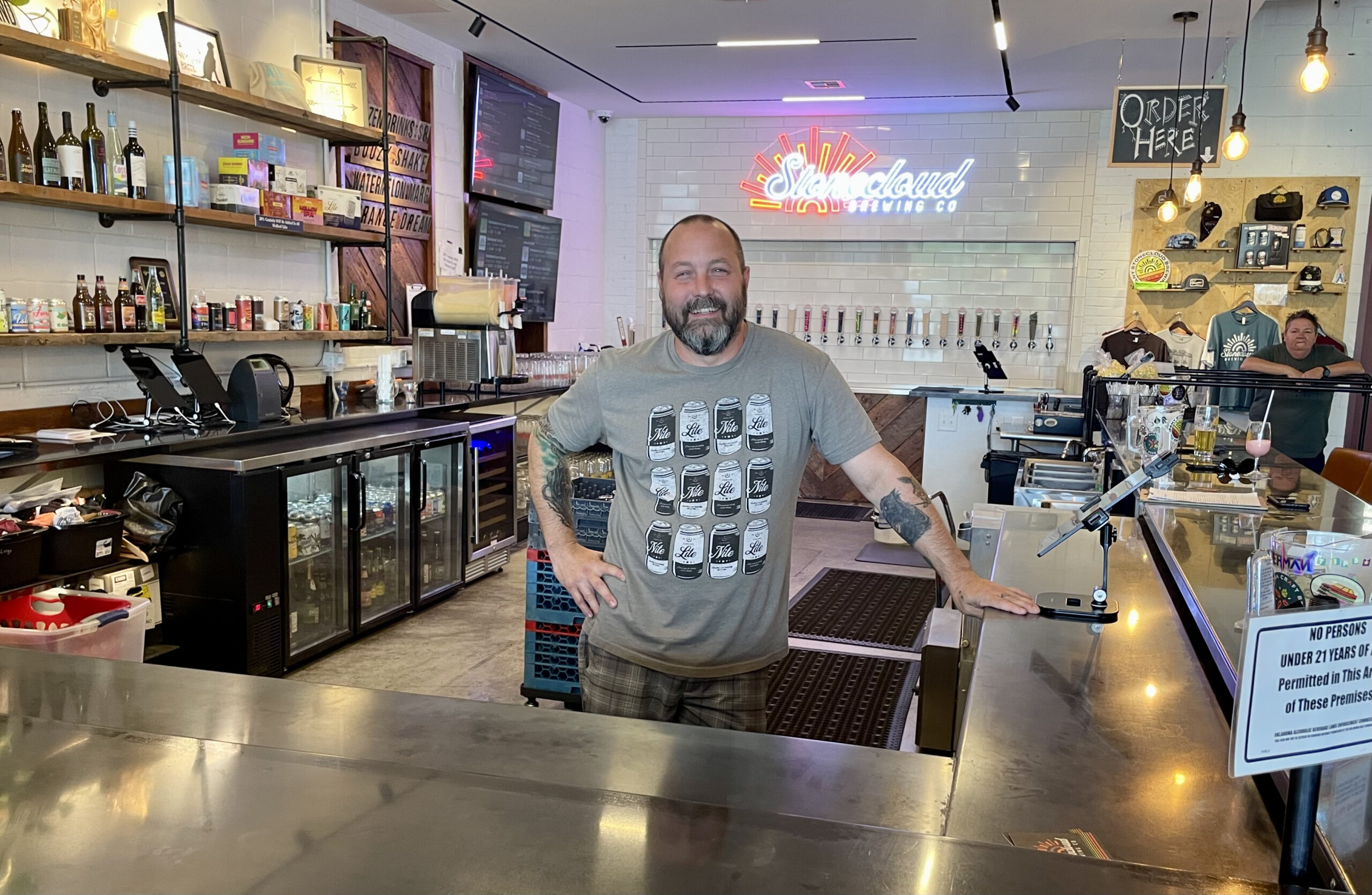 Man stands behind a bar in a brewery.